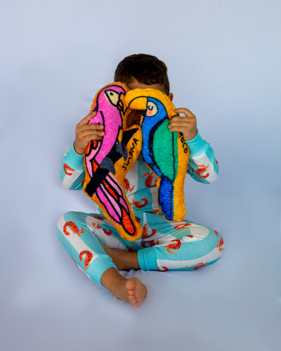 Niño en pijama con dos peluches de guacamaya