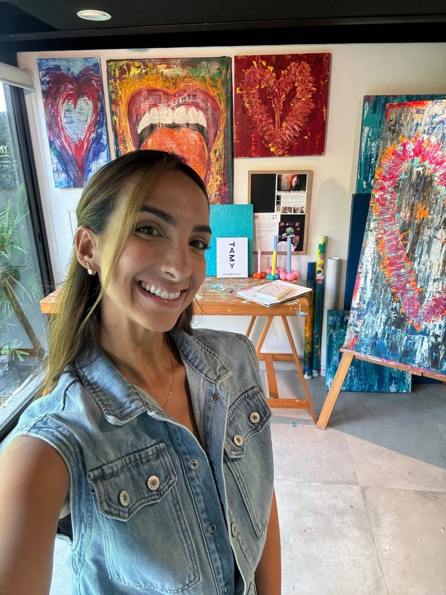 Tamy González en su estudio, con sus obras al fondo