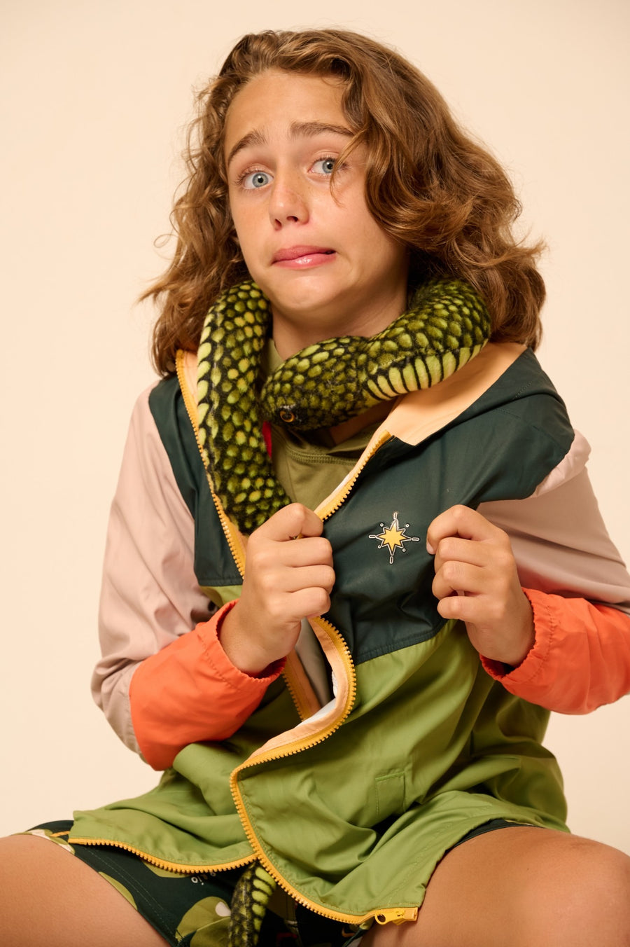 Niño con cortaviento Capitán Río y una serpiente de peluche al cuello