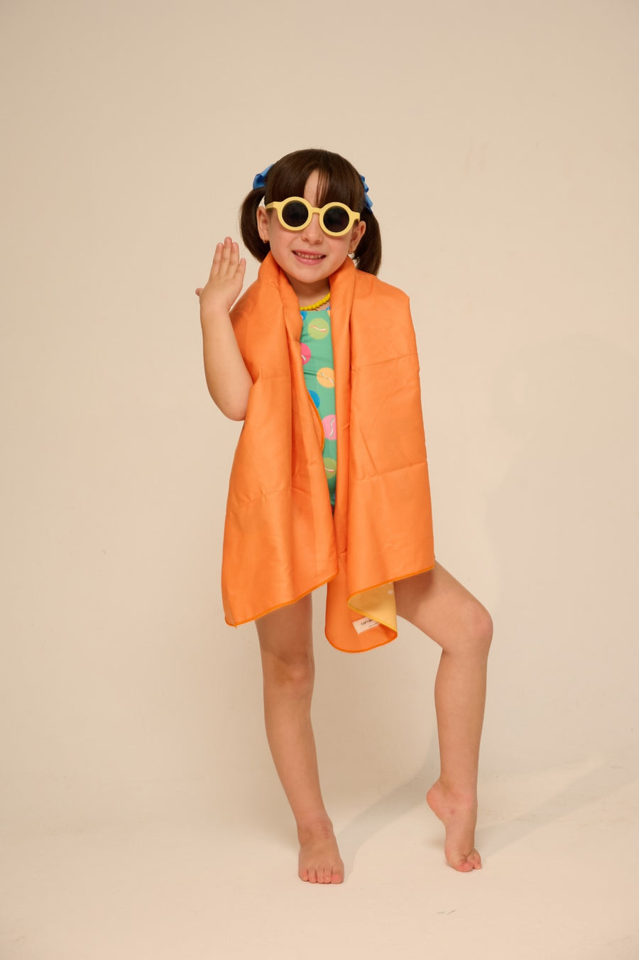 Niña con lentes de sol y toalla naranja